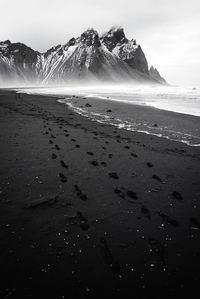 Scenic view of sea by mountain against sky