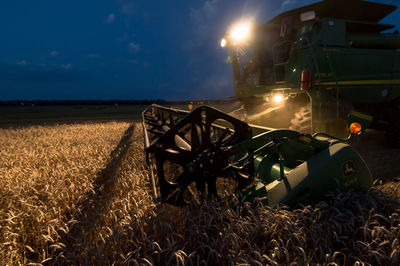 Illuminated machinery harvesting plants on field