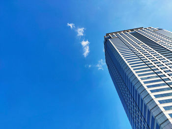 Low angle view of skyscraper against blue sky