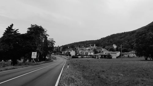 Road by trees against sky