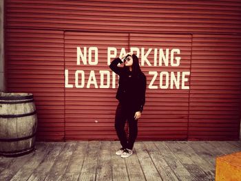 Full length of woman standing against wall