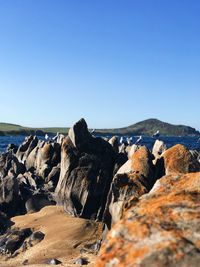 Rocks on beach against clear blue sky