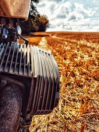 Close-up of machinery on field against sky