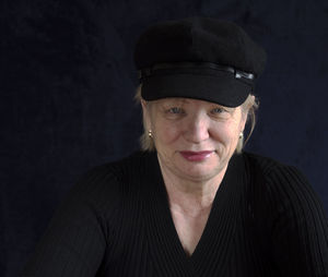 Portrait of smiling mature woman with cap against black background