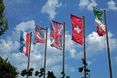 Low angle view of american italian switzerland flags against sky