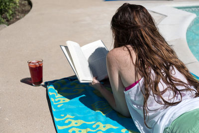 Rear view of woman reading book in swimming pool