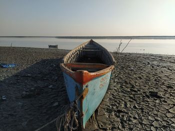 Boat moored on beach against sky during sunset