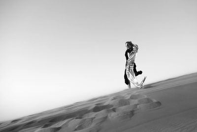 Full length of woman standing in desert against sky