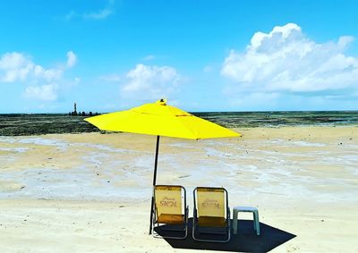 Yellow umbrella on beach against sky