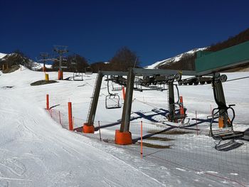 Snow covered field by mountain against clear sky