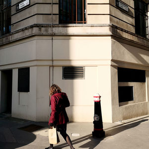 Rear view of woman walking on street by building