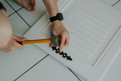 A young guy is repairing a retro lock on a locker door.