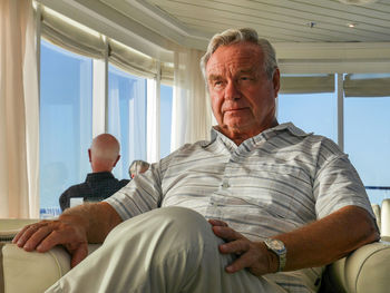 Portrait of man sitting on window