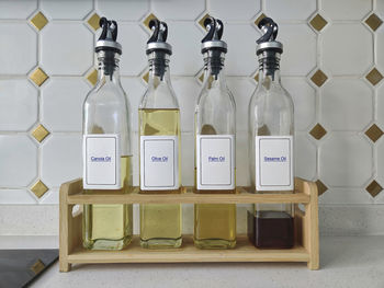 Row of cooking oil in glass bottles in a wooden rack