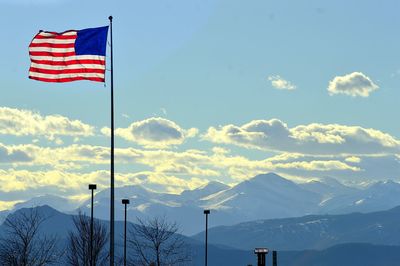 American flag by mountains against sky