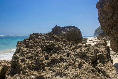 Rock formation on beach against clear blue sky