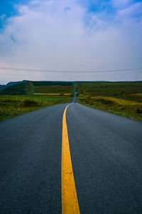 Road amidst field against sky