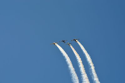 Low angle view of airplane flying against clear blue sky