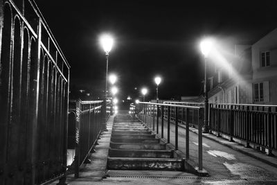 Empty footpath along illuminated street lights at night