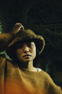 Portrait of young woman wearing hood at illuminated restaurant