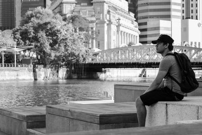 Young woman sitting by fountain in city