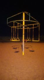 Low angle view of illuminated lighting equipment on beach against sky