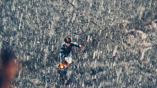 High angle view of boy running on street during rainy season