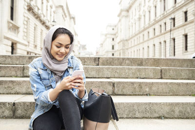 Uk, england, london, young woman wearing hijab using cell phone in the city