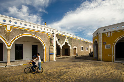 Man riding motorcycle on building against sky