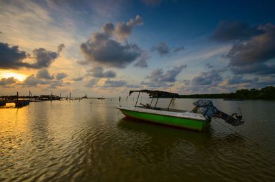 Boats moored in sea against sky during sunset