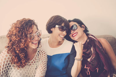 Cheerful friends wearing sunglasses while sitting on sofa