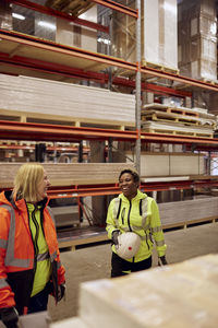 Happy multiracial female coworkers standing in distribution warehouse