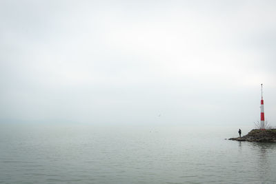 Pier with angler on foggy lake