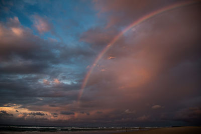Scenic view of rainbow over sea against dramatic sky