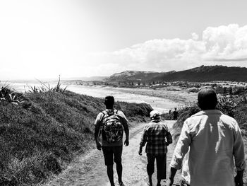 Rear view of people walking on mountain against sky