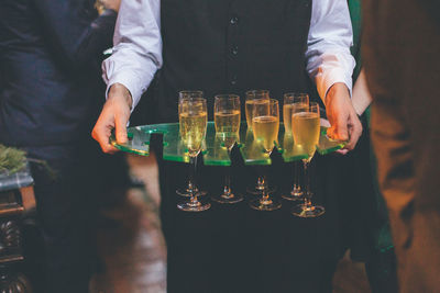 Midsection of waiter carrying champagne