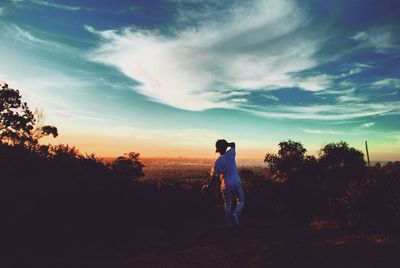 Full length of man photographing on field against sky during sunset