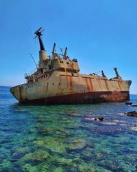 Damaged ship on sea against clear sky