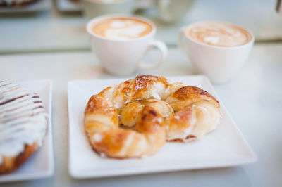 High angle view of croissant with cappuccinos served on table