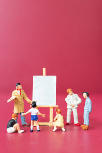 Full length of father with toy standing against red background