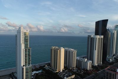 Modern buildings by sea against sky