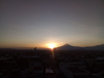 Silhouette cityscape against sky during sunset