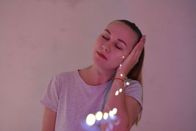 Close-up portrait of young woman against pink wall