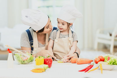 Mother and daughter on cutting board in kitchen