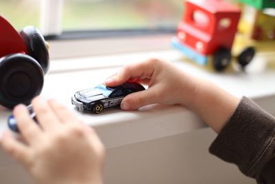 Cropped image of boy playing with toy car at home