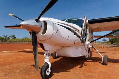 Close-up of airplane on runway against blue sky