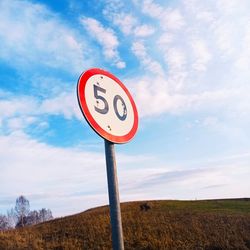 Low angle view of road sign against sky