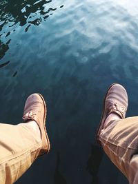 Low section of man wearing shoes over lake