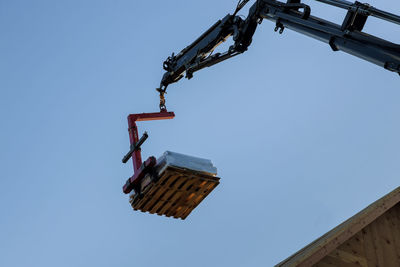 Low angle view of crane against clear blue sky