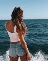 Rear view of woman standing in sea against sky